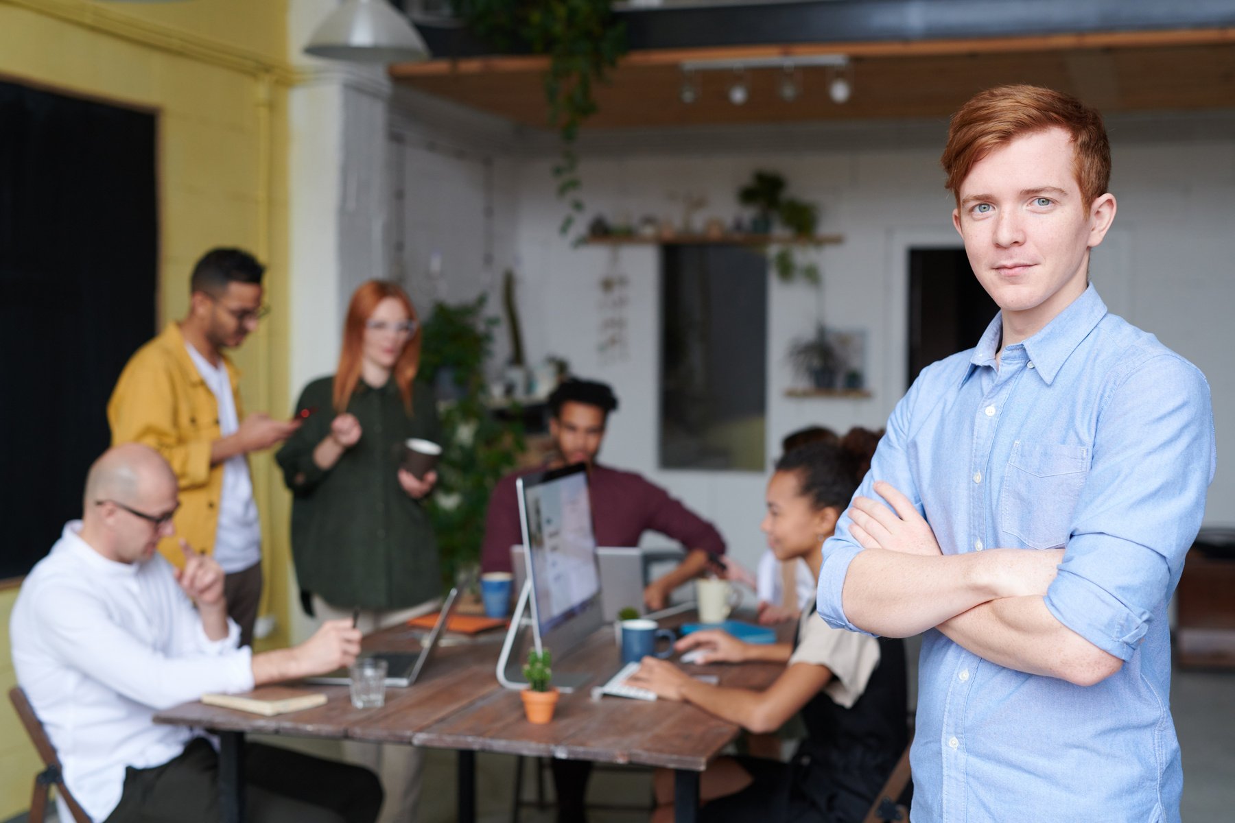 Man Standing Beside People Sitting Beside Table With Laptops